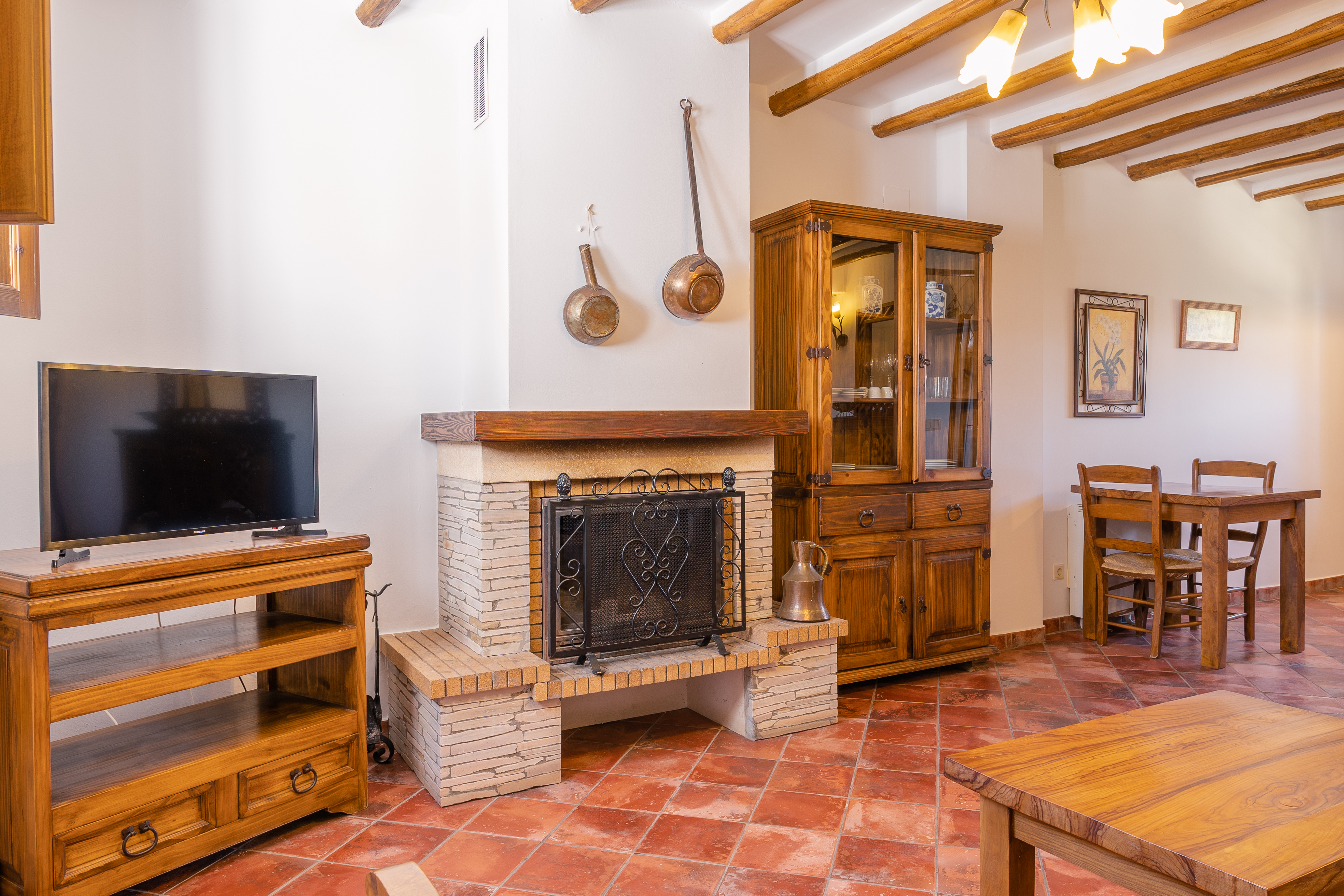 Interior of a holiday apartment showing living area with wooden ceiling beams and tiled floor