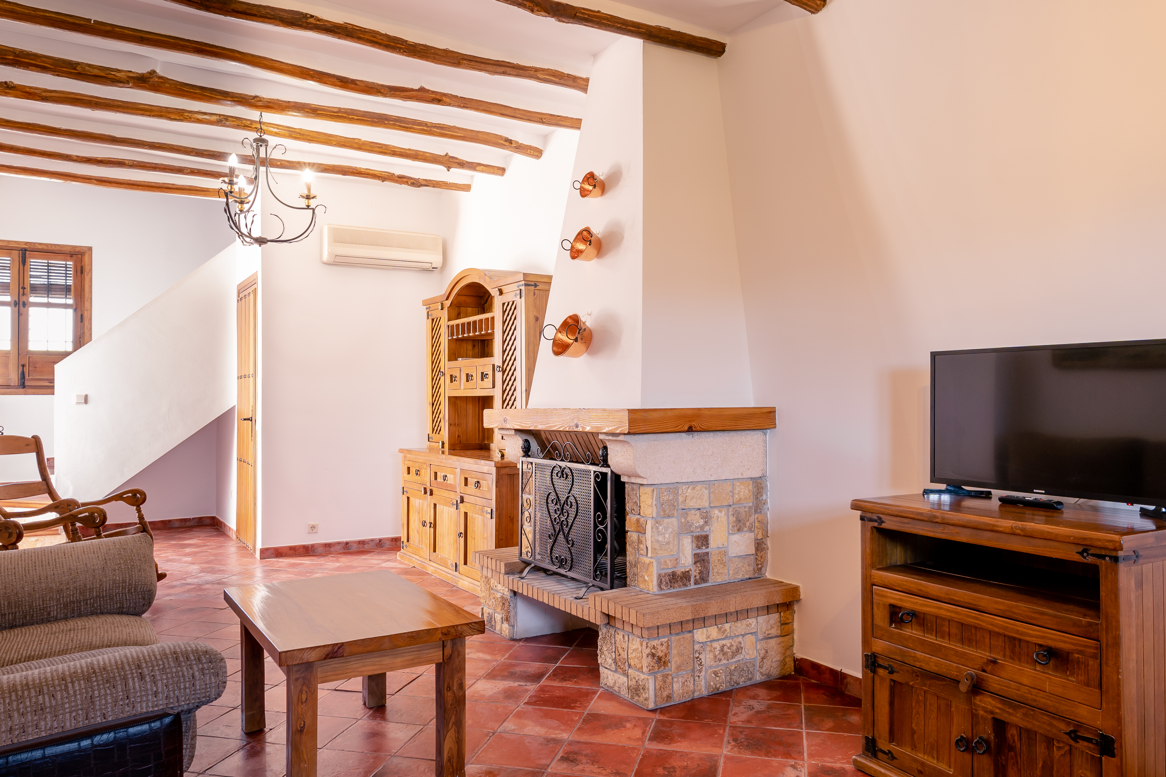 Interior of a holiday apartment showing living area with wooden ceiling beams and tiled floor