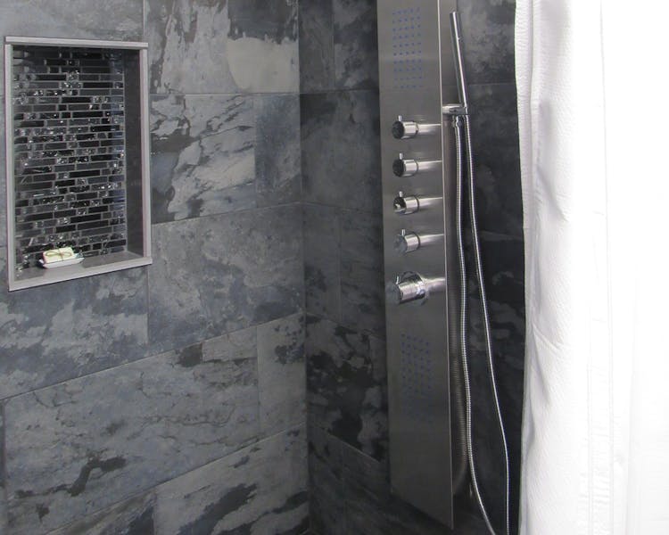 Dark slate stone for the walk in showers. A large body shower panel with rainfall or waterfall abilities.
