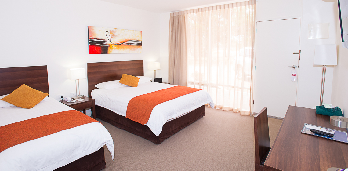 Modern hotel room with two beds and artwork.