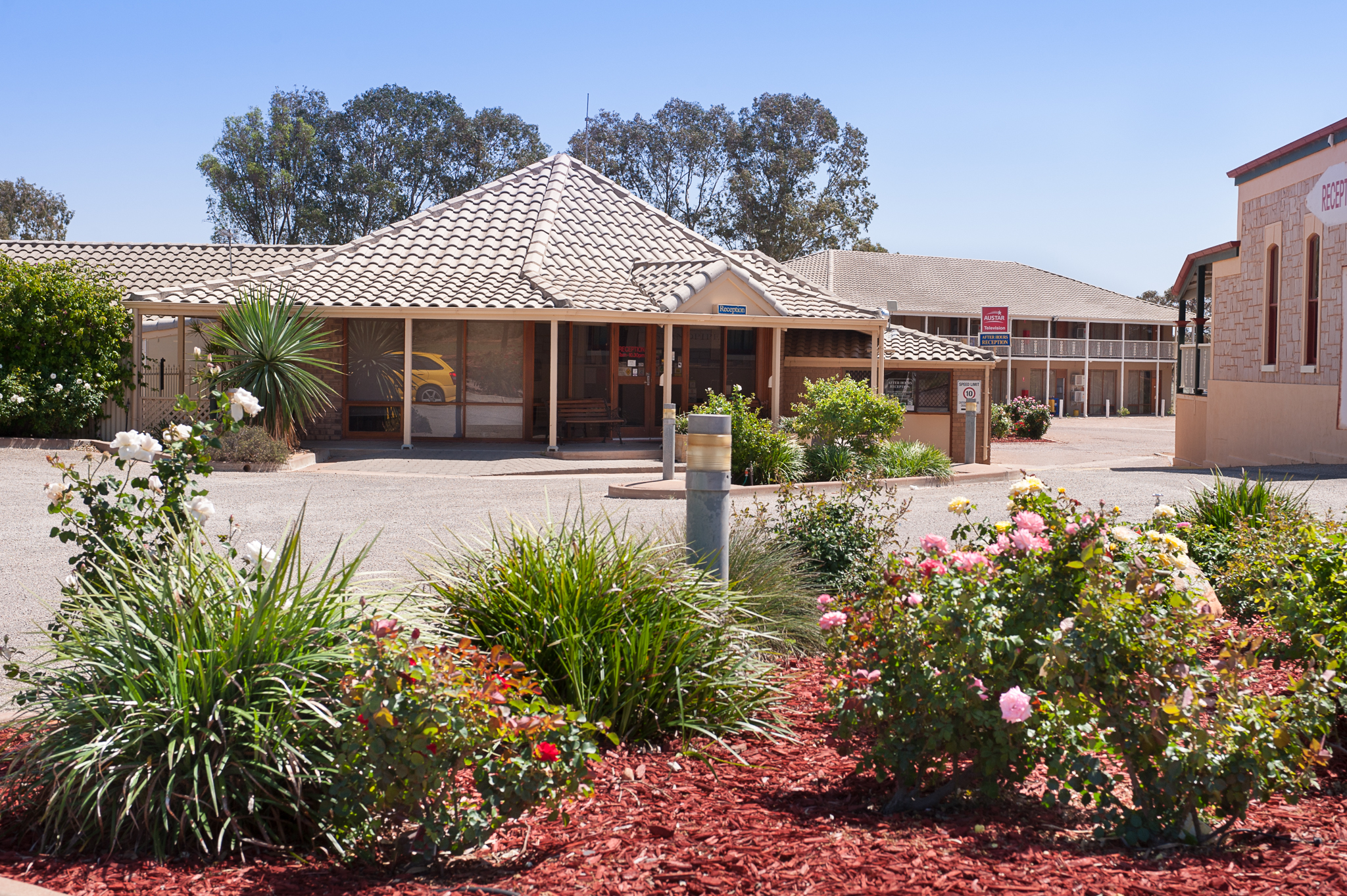 Standpipe Inn & Golf, Red roofs, green lawns, Flowers in bright bloom, A classic motel scene, Under clear blue sky.