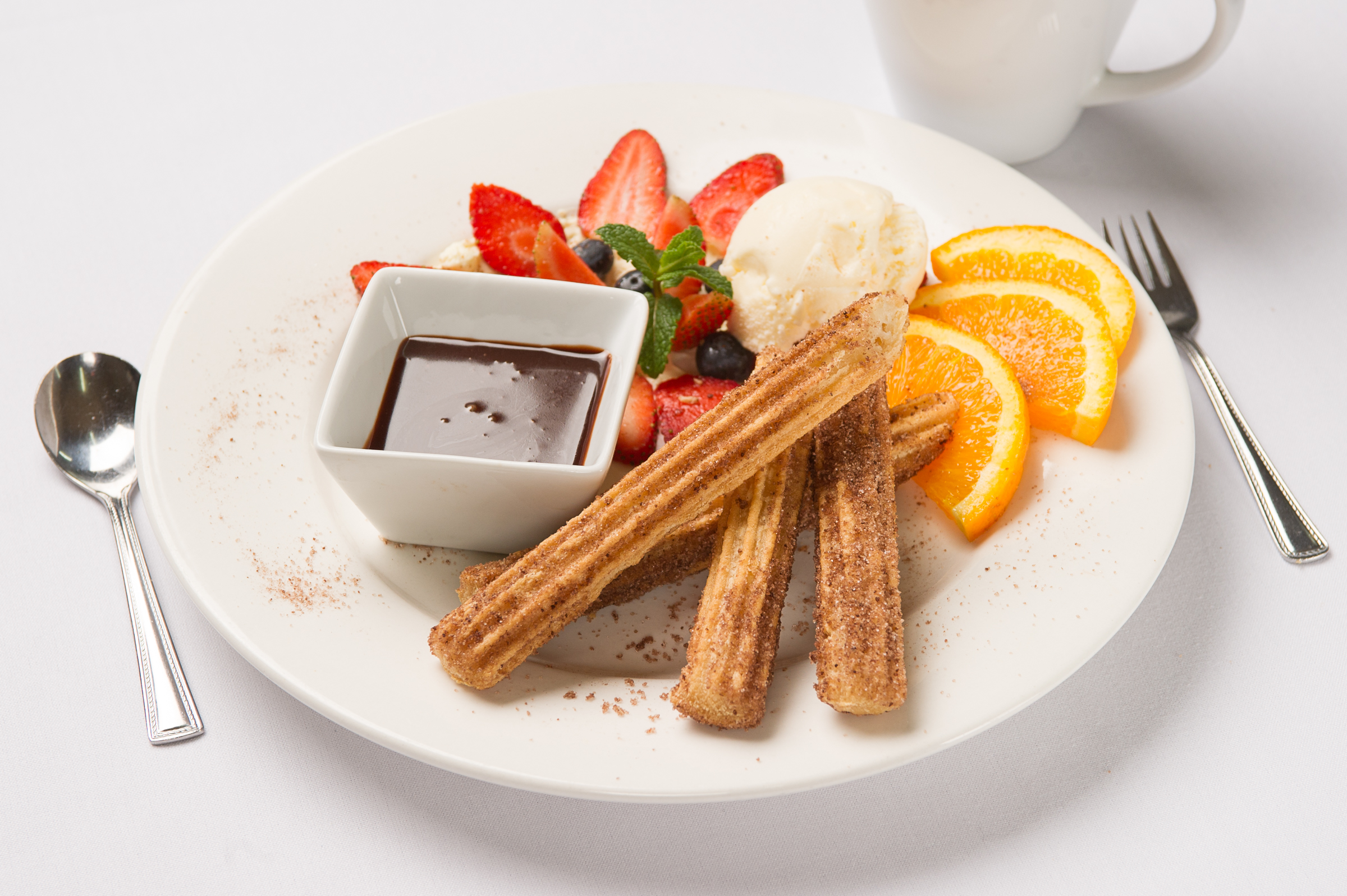 Delicious churros with chocolate, ice cream, and fruit.