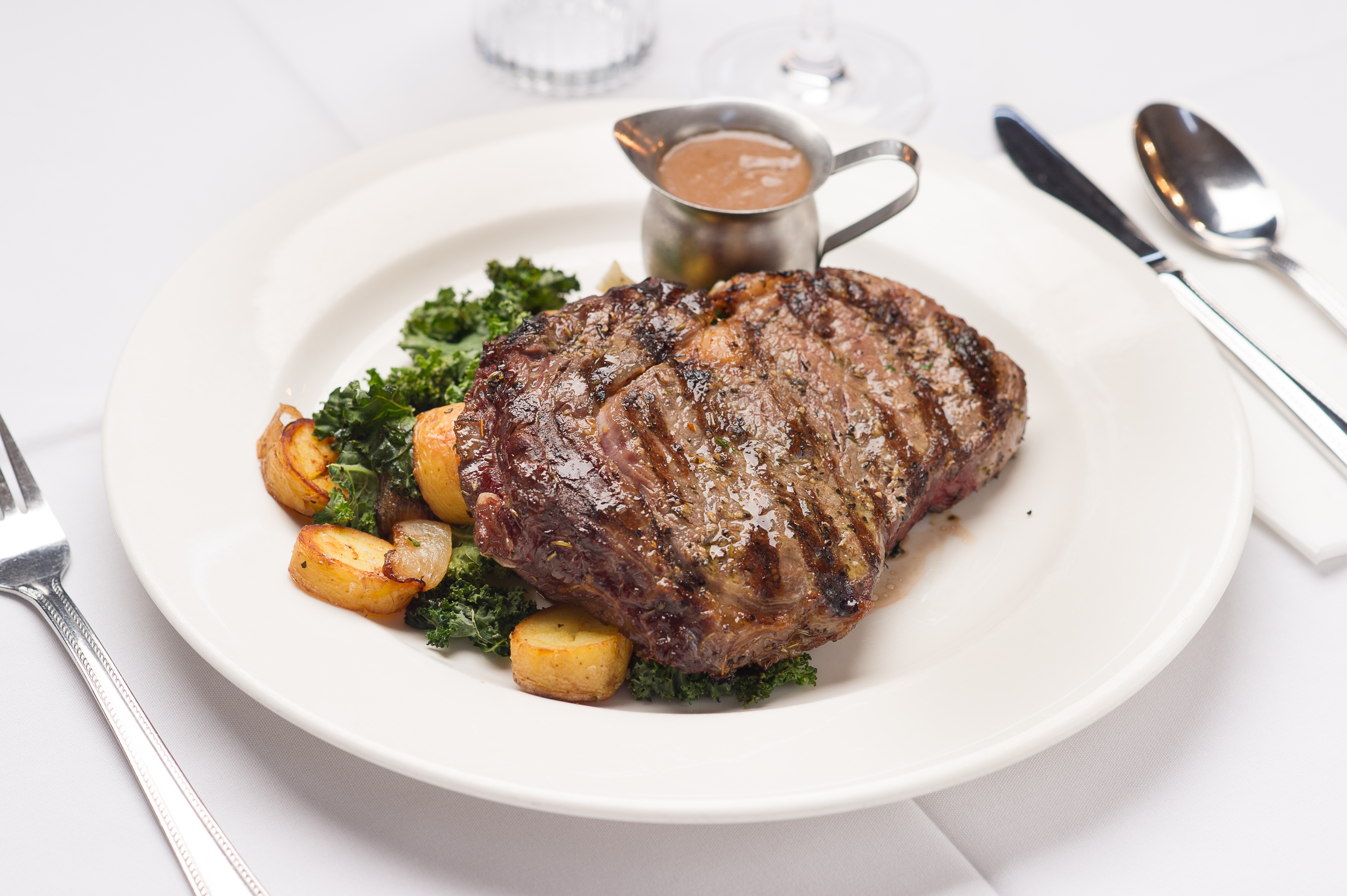 Perfectly grilled ribeye steak, roasted potatoes, and wilted greens.