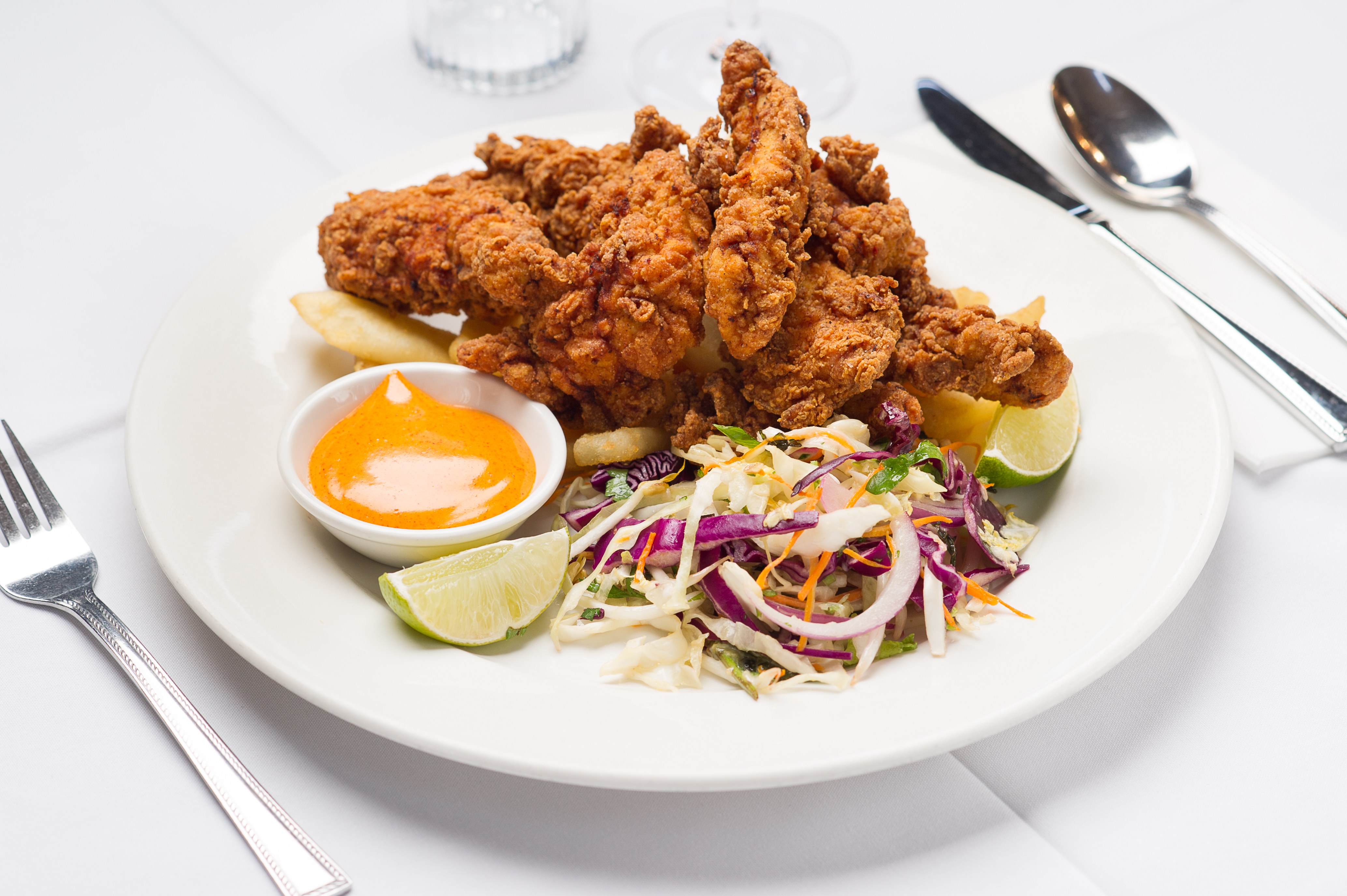 Crispy fried chicken tenders, vibrant slaw, zesty dip, lime.