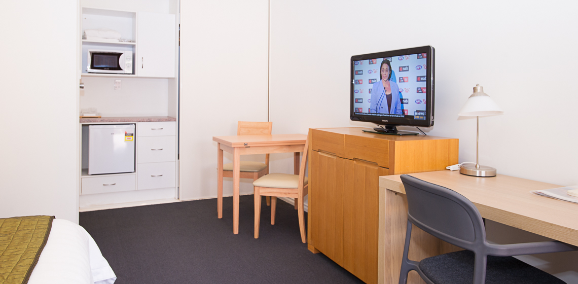 Clean, modern room with microwave, TV, and workspace.