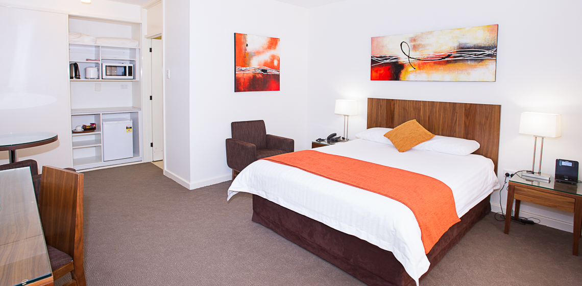 Modern hotel room with vibrant art, queen bed, and Microwave.