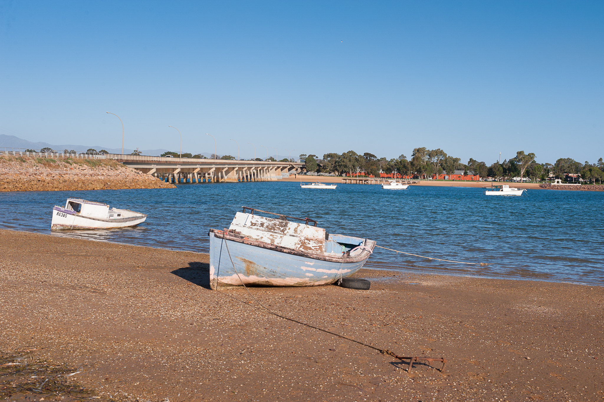 Boat, shore, bridge, calm waters.