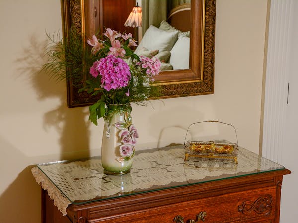 Bureau with a vase of flowers in the Rapunzel Suite.