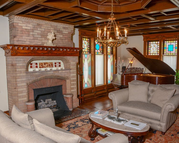 Music room showing fireplace, couches and piano.