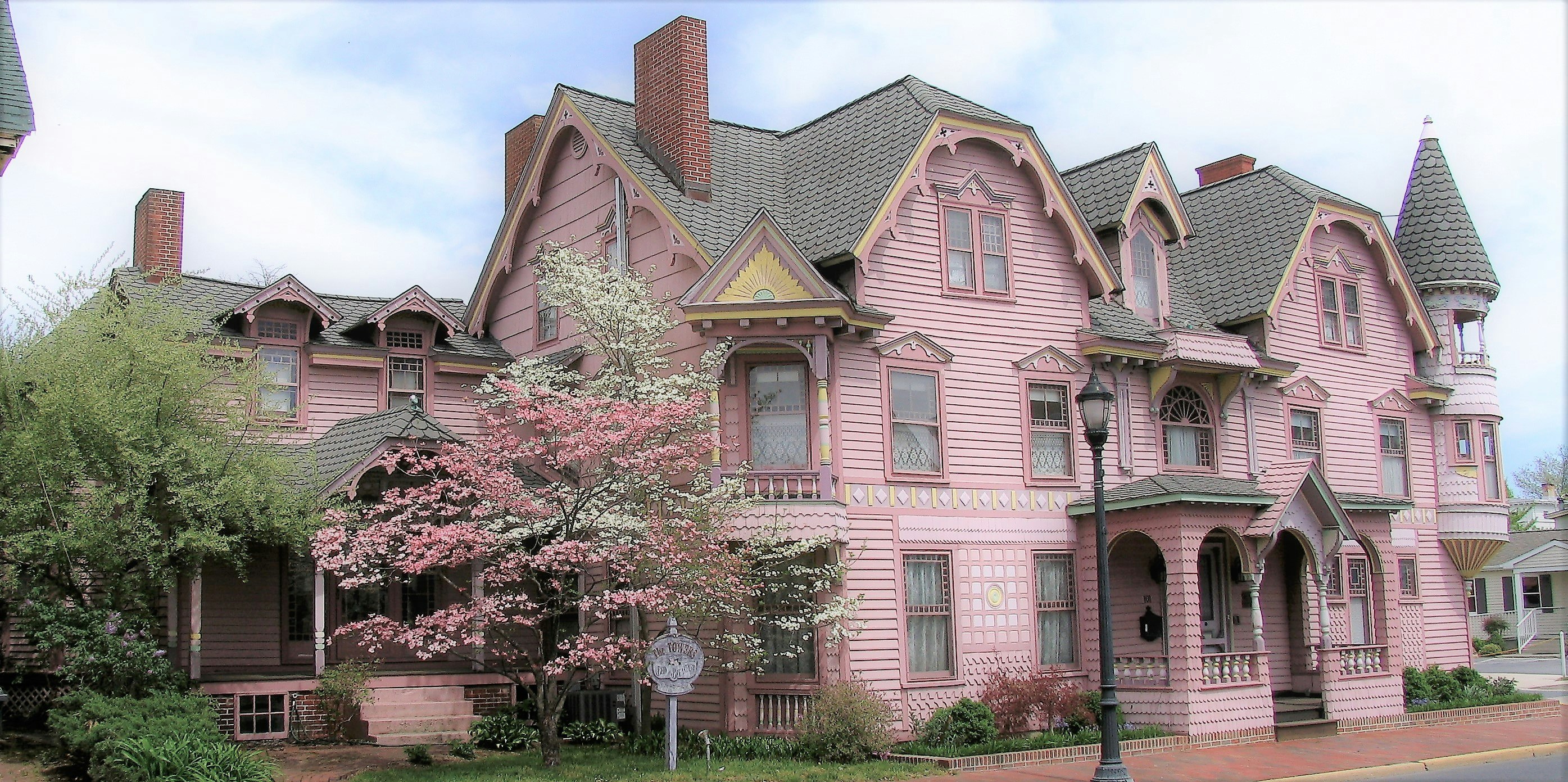 A large pink house with a gray roof and a tree in front of it