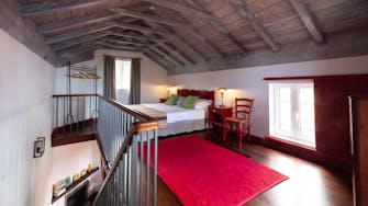 Bedroom in cottage, red carpet, red painted furniture, glimpse of fireplace, Quinta das Vinhas self-catering, Madeira island