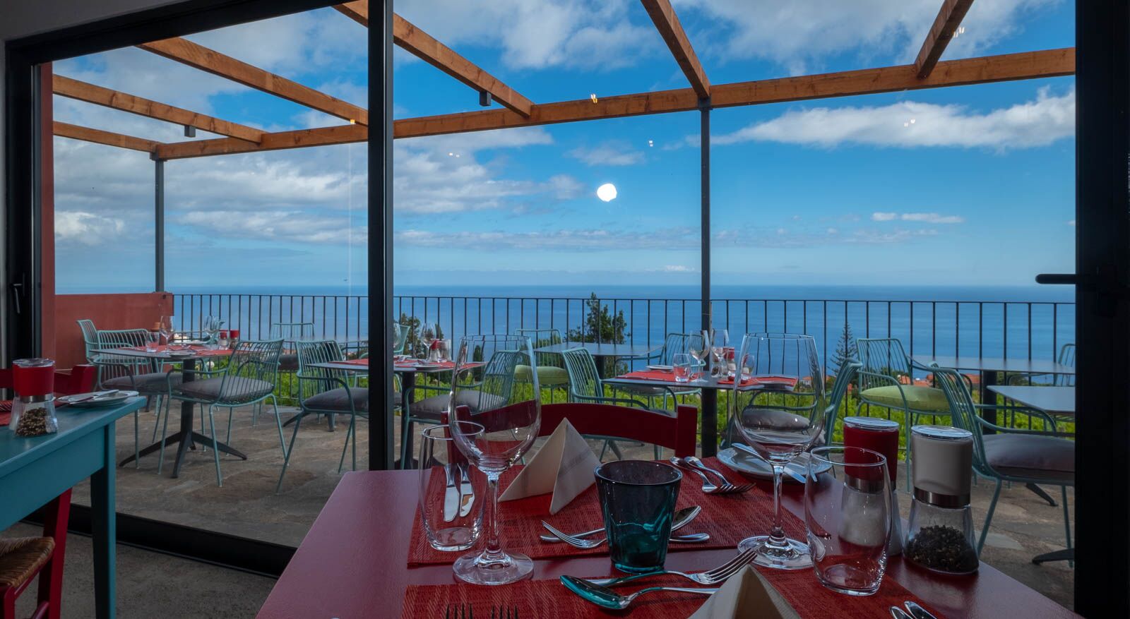 View from the wine bar restaurant with blue sky, green vineyard, and blue sea beyond