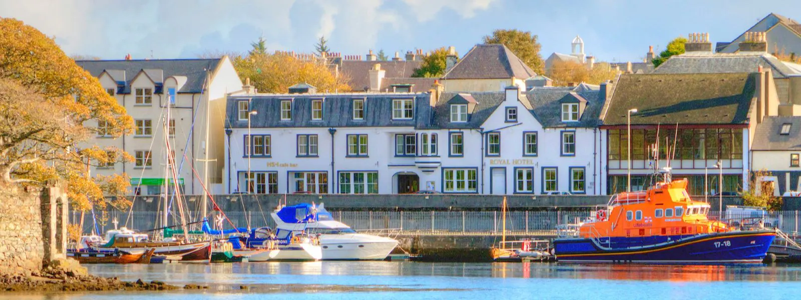 View from the Lews Castle Grounds overlooking the Stornoway harbour with boats and the Royal Hotel in behind it.
