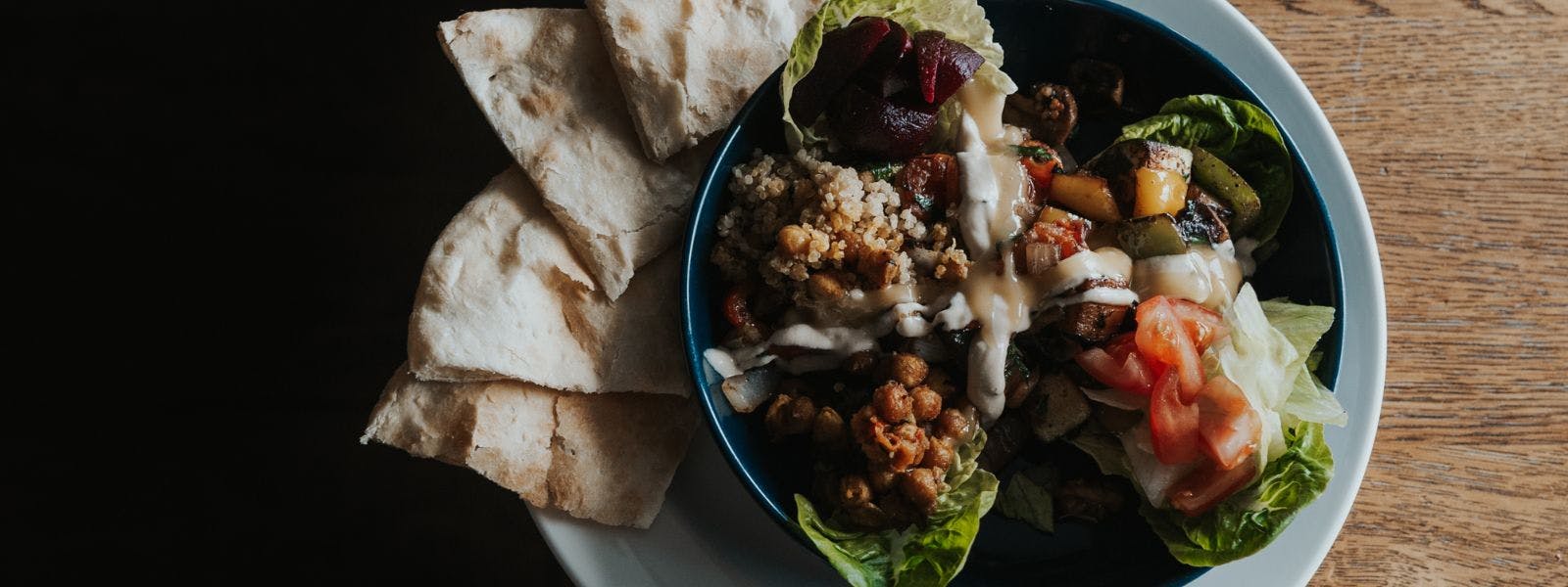 A plate of food with a fresh salad and pita bread, a delicious and healthy meal option.