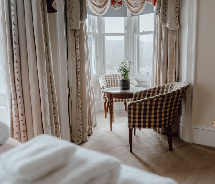A hotel room with a chair and table, providing a comfortable space for guests to relax and work.