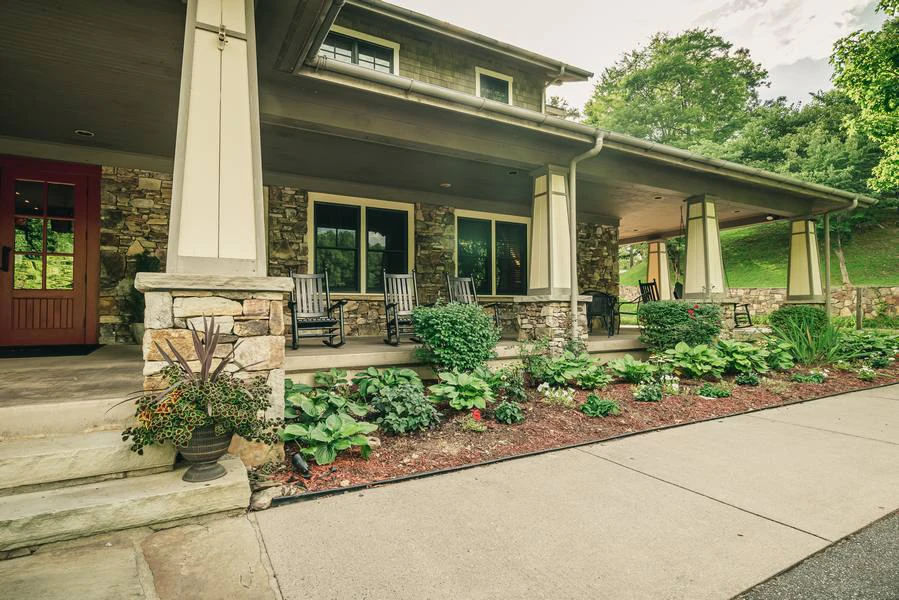 A stone building with a large porch and plants in front.