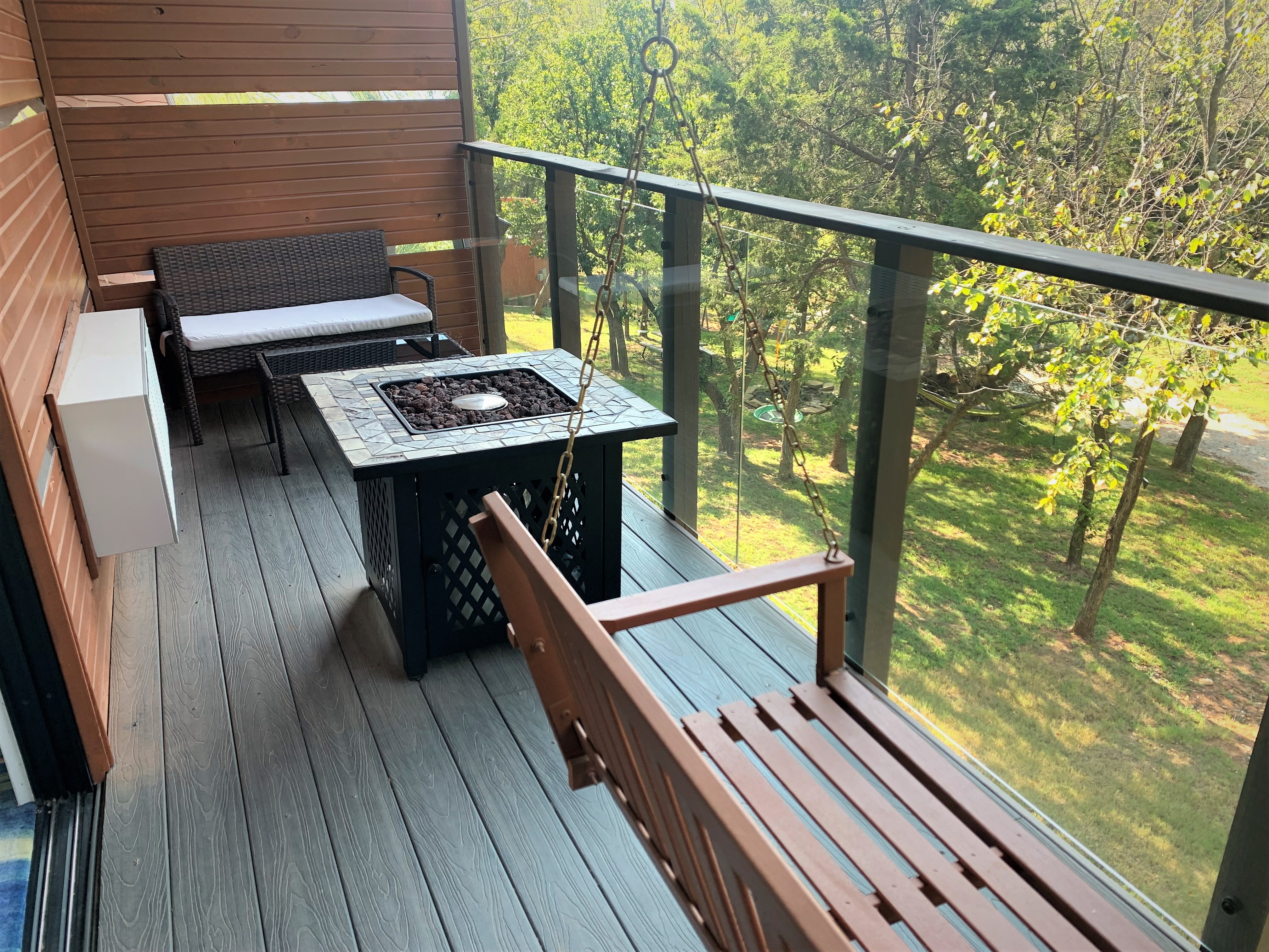 Spacious private balcony with swing, fire pit, and seating area