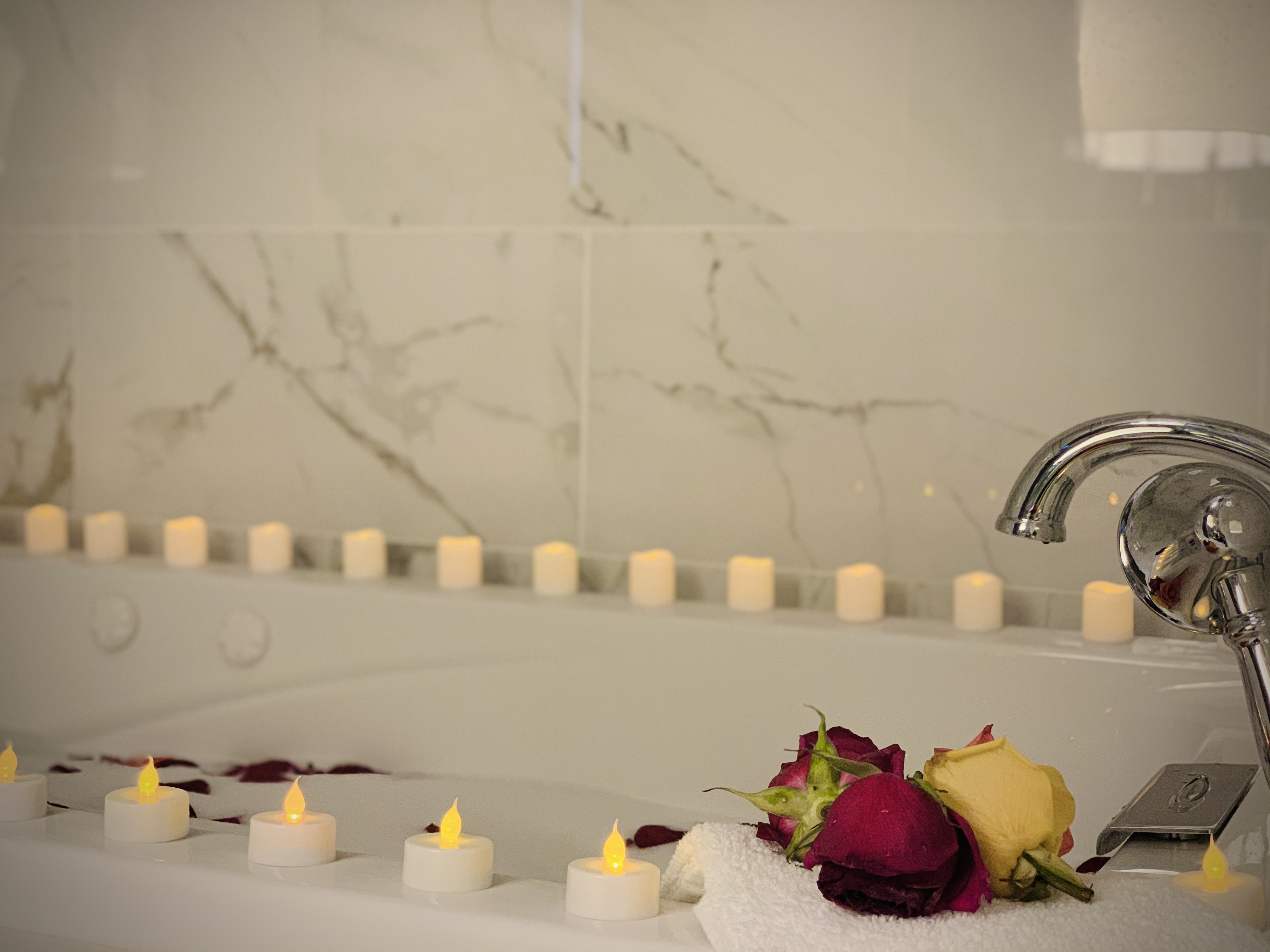 Romantic jacuzzi setup at WangShi Palace — candles and rose petals for a relaxing, intimate experience.