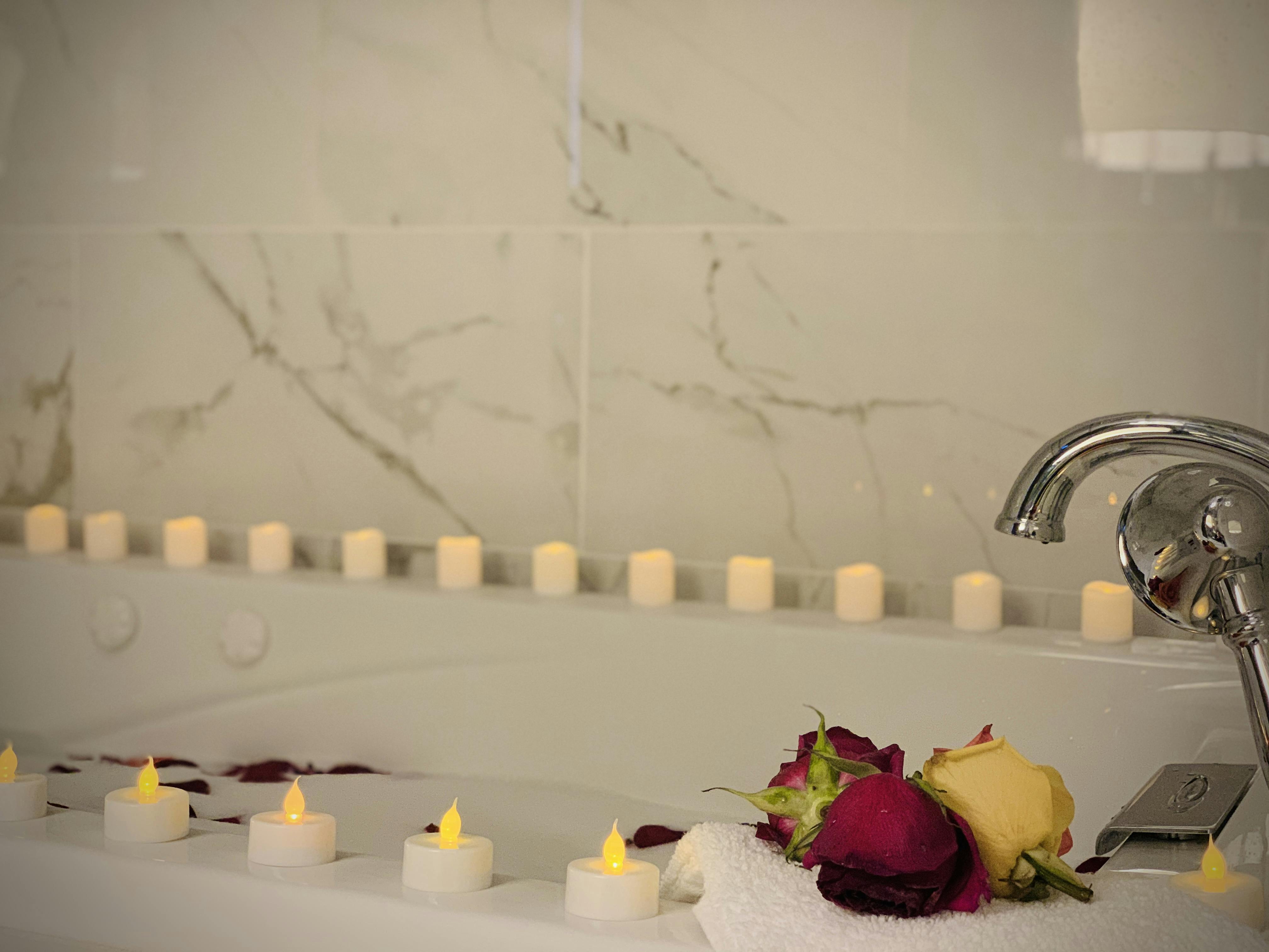 Romantic jacuzzi setup at WangShi Palace — candles and rose petals for a relaxing, intimate experience.