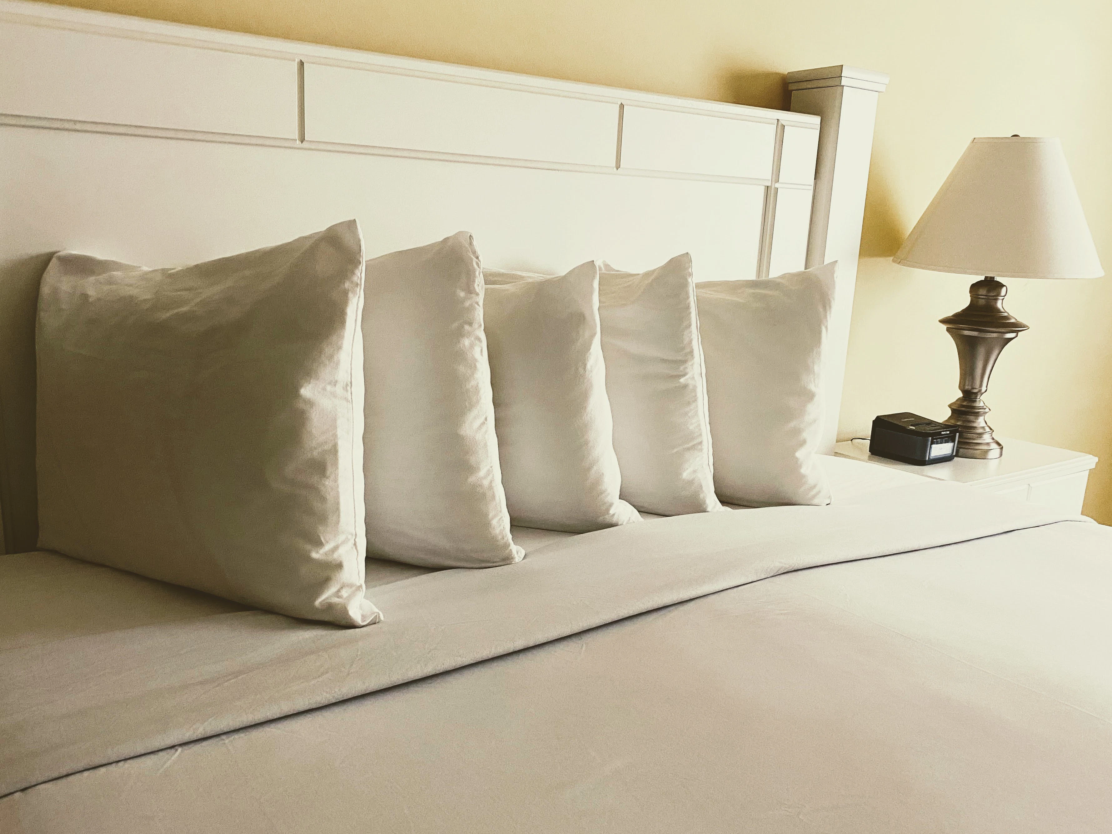 A close-up of a bed with white pillows and a lamp on a nightstand