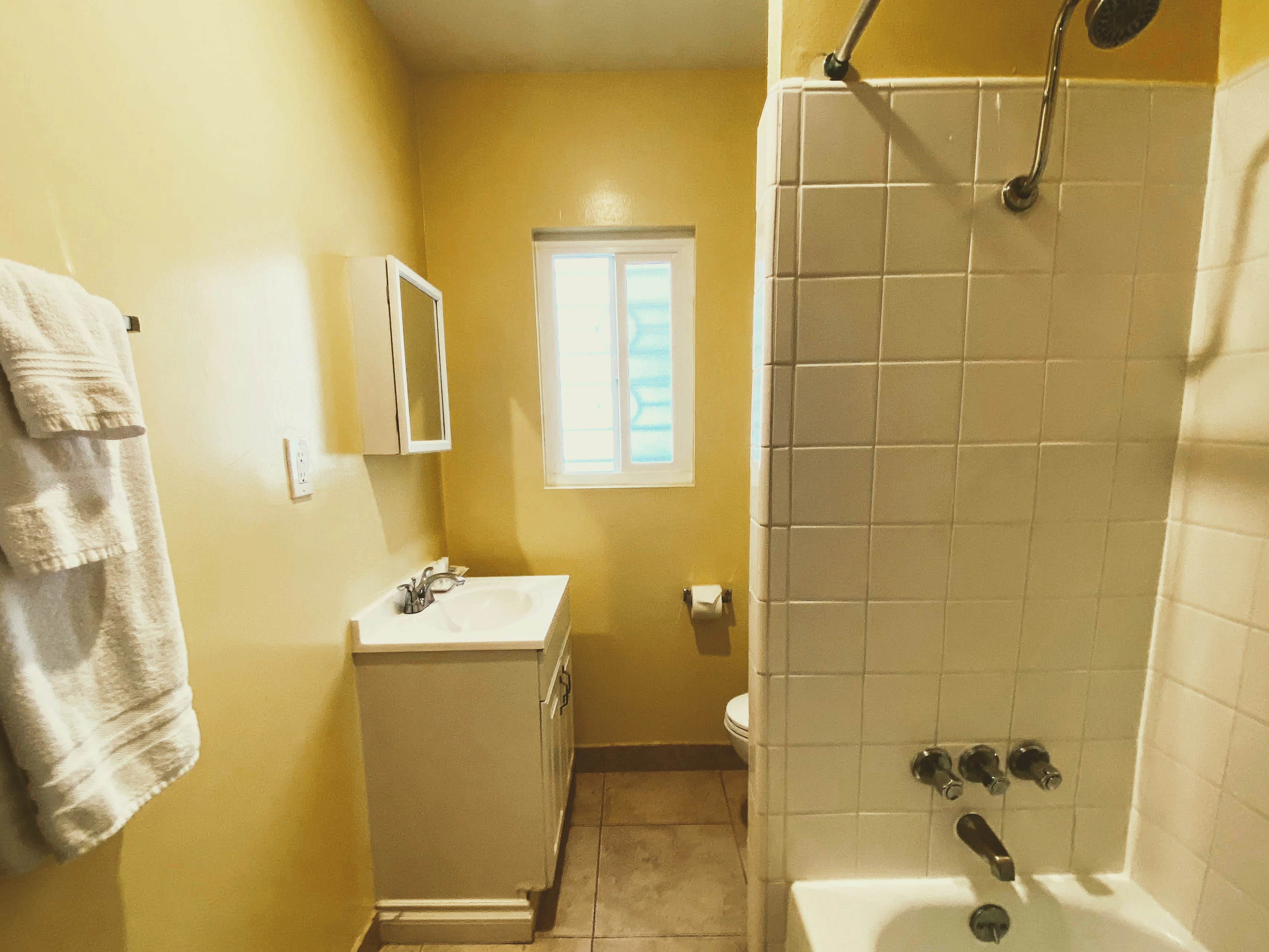 A standard bathroom with a tiled shower, tub, sink, and toilet.