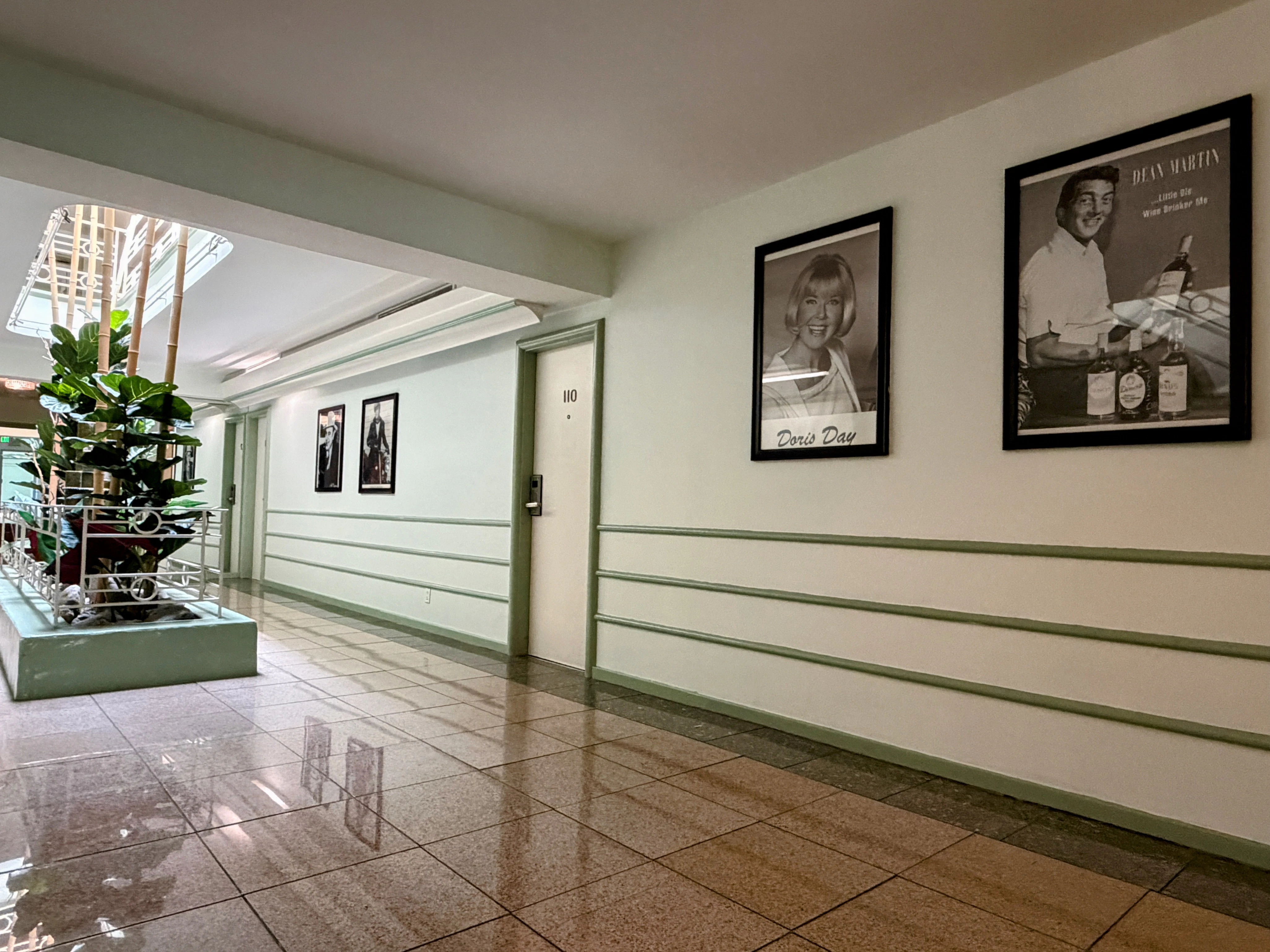 A lobby with green trim, tile floor, and framed photos on the wall.