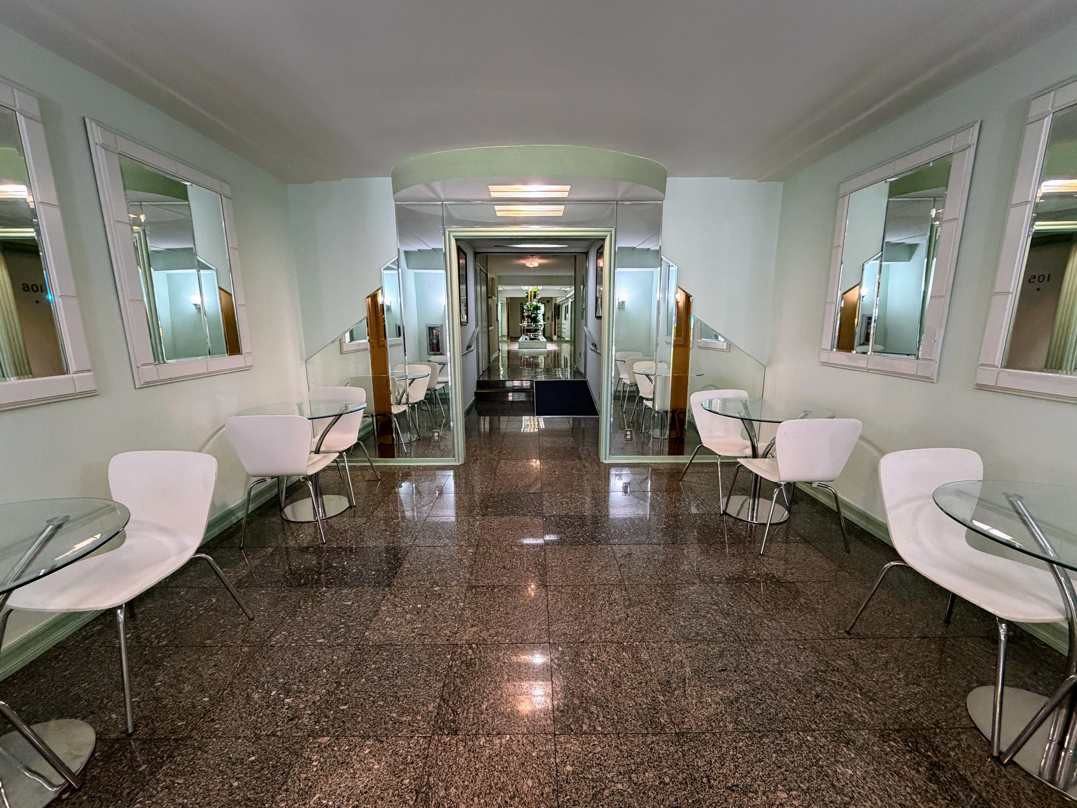A wide lobby with a polished floor, arched ceiling, and mirrors on the walls.
