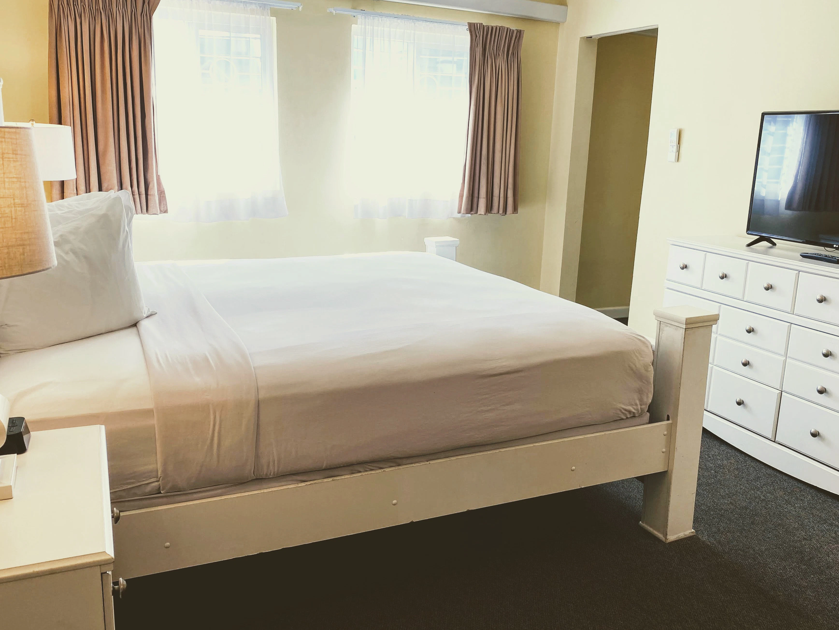 A wide view of a hotel room with a bed, dresser, and TV