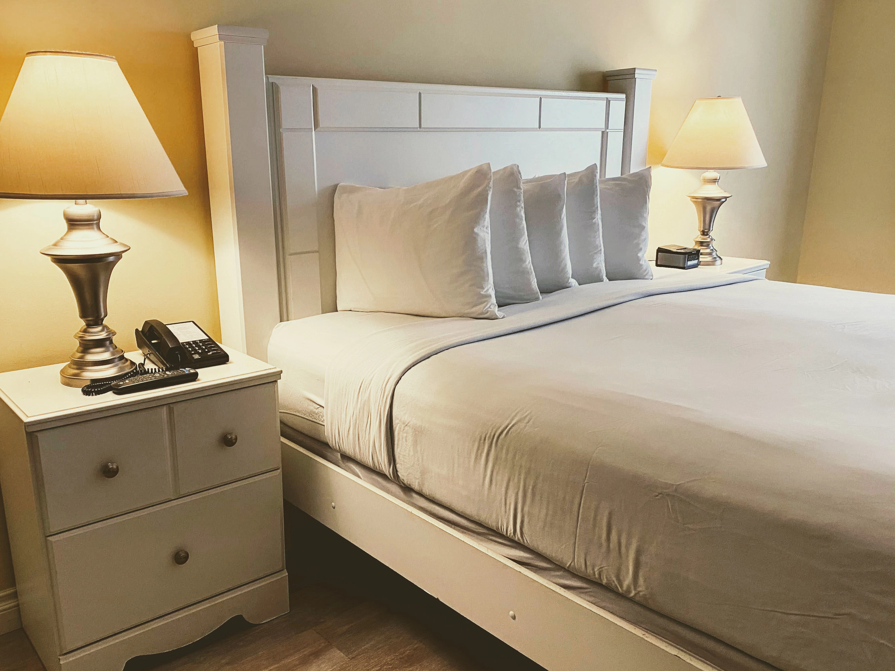 A white bed with two lamps and a telephone on the nightstand