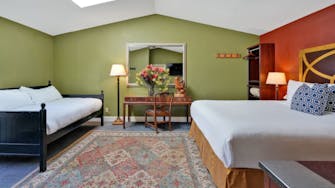 bed writing desk, and day bed in background of deluxe room