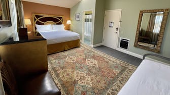 Room interior with rug and bathroom side view. King and and twin bed.